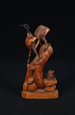 une sculpture en bois représentant un cerf et un chat sur un rocher
