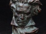 bronze bust of a man with long hair on a black background