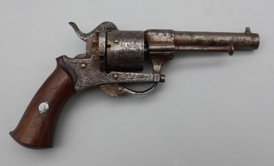 un vieux revolver avec une poignée en bois sur une surface blanche