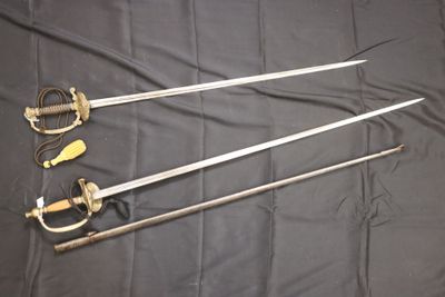 trois épées sont posées sur un tissu noir, sur une table