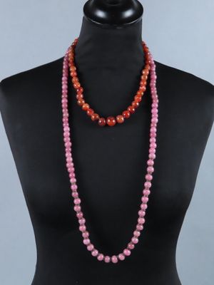 un collier de perles roses et rouges sur un buste de mannequin