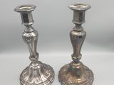 deux bougeoirs en argent posés sur une table blanche