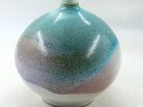 un vase bleu et violet posé sur une surface blanche