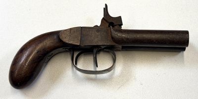 un vieux pistolet avec une poignée en bois sur une surface blanche