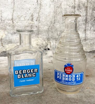 deux bouteilles d'alcool posées l'une à côté de l'autre par terre