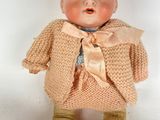 a small doll that is wearing a sweater and pants