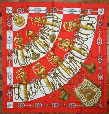 une écharpe rouge et blanche ornée d'un motif doré, posée sur un parquet