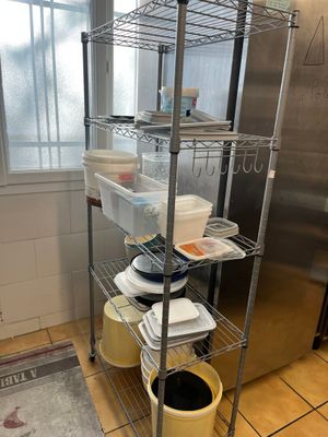 une cuisine équipée d'une étagère en inox sur laquelle sont posés de nombreux plats