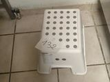 a white step stool sitting on the floor in a bathroom