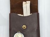 étui en cuir marron avec une poche pour une montre et une poche pour une montre de poche
