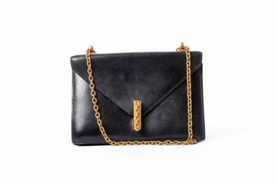 un sac à bandoulière en cuir noir muni d'une bandoulière en chaîne dorée