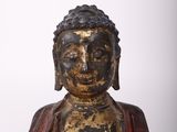 an old statue of a buddha sitting on a white surface