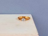 un gros plan d'une bague en or surmontée d'un diamant blanc