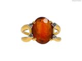 un gros plan d'une bague sertie d'une pierre orange et de diamants