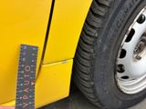 someone is measuring the width of a tire on a yellow bus