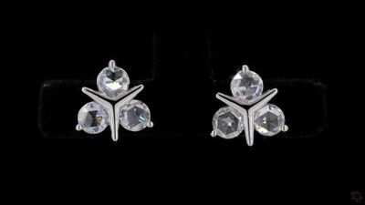 pair of white crystal earrings on black background with reflection