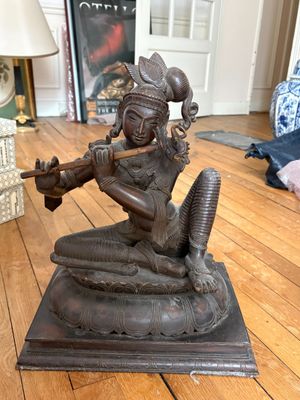 une statue représentant une femme jouant de la flûte sur un parquet