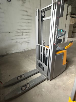 un chariot élévateur dans un entrepôt, équipé de fourches jaunes