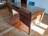 a wooden desk with a glass top and a blue chair