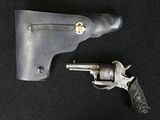 un pistolet posé à côté d'un étui, sur fond noir