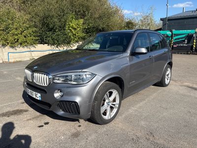 the bmw x5 is parked in a parking lot near a building