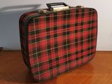 a red and black plaid suitcase sitting on a wooden table