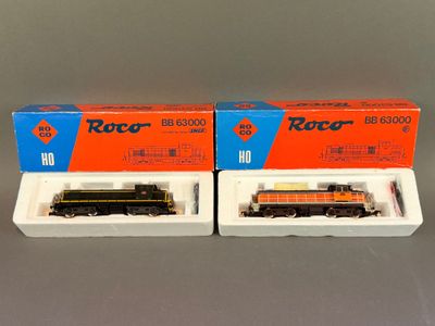 Deux trains miniatures sont rangés dans des boîtes posées sur une table