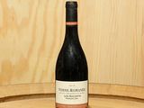 a bottle of wine sitting on top of a barrel