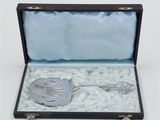 an antique silver spoon and spoon rest in a black case