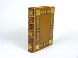 un vieux livre avec des bordures dorées et des motifs décoratifs sur la couverture