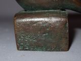 a bronze statue of a bird sitting on top of a block