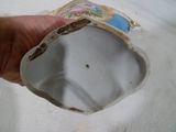une main tenant un vase en porcelaine blanche avec une photo dessus