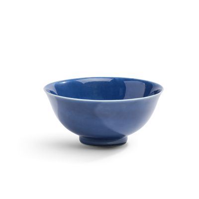 un bol bleu posé sur une surface blanche, sur fond blanc