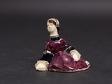 an old figurine of a woman in a red dress sitting on a black surface