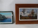 painting of a river and a picture of a city in a wooden frame