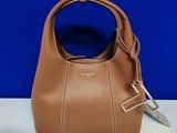 un sac à main marron muni d'une poignée en métal, posé sur une table blanche