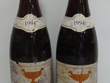 two bottles of red wine sitting next to each other on a table