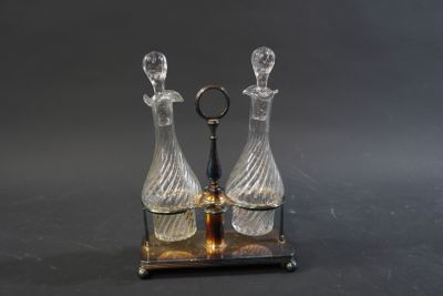 une paire de carafes en verre posées sur un socle en métal, sur fond noir
