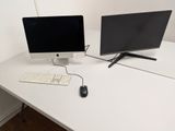 deux écrans d'ordinateur et un clavier posés sur un bureau blanc