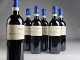 six bottles of wine are lined up in a row on a white surface