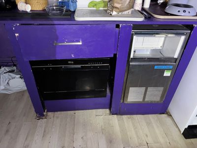 une cuisine violette avec un réfrigérateur et un lave-vaisselle posés sur le plan de travail