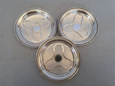 three silver plated dishes on a table with a white table cloth