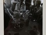 une photo en noir et blanc montrant un groupe de personnes assises à une table