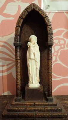 une statue représentant une femme tenant un enfant dans ses bras devant un mur