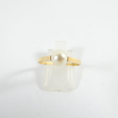 a close up of a ring with a pearl in it on a white surface