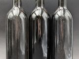 three bottles of wine are lined up on a gray surface