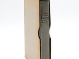 an old book sitting on top of a cardboard box on a white surface