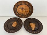 trois assiettes en bois sur lesquelles sont sculptées des figures d'hommes et de femmes