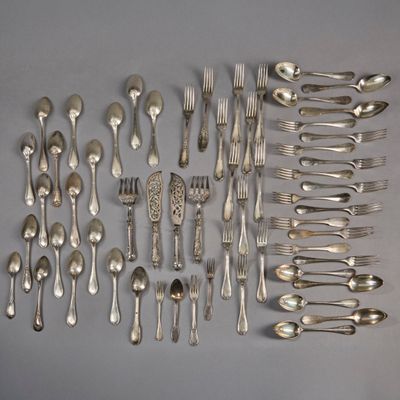 a lot of silver spoons and forks laid out on the table