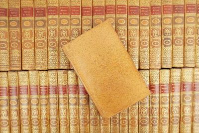 a stack of old books on a shelf next to each other